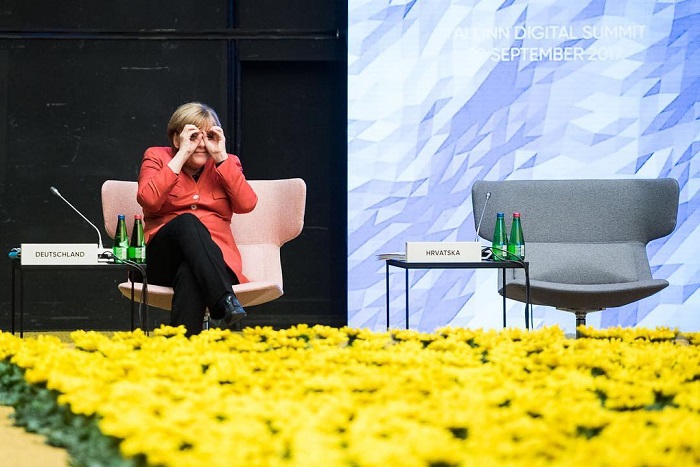На Европейском саммите в Таллине Меркель шутливо отреагировала на собеседника, который находился в другом конце зала, и изобразила руками бинокль.