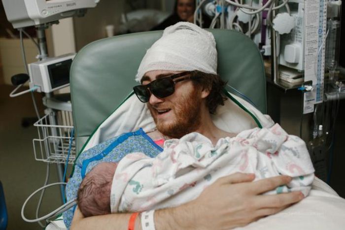 Мужчина, который проходит лечение, держит на руках новорожденного сына.