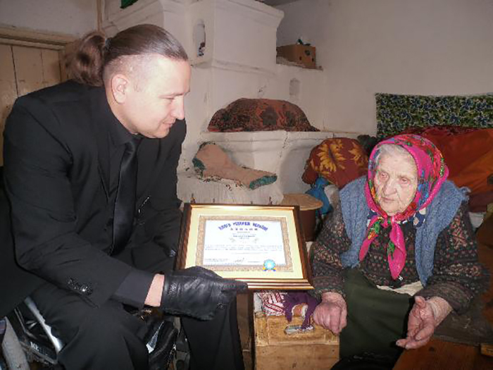 Кристине Нагорной вручают диплом долгожителя.
