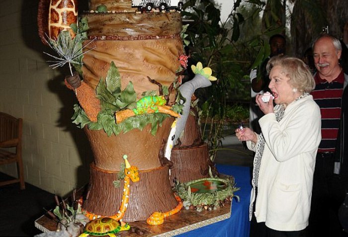 Бетти Уайт пробует кусочек тематического торта, который приготовили к ее дню рождения в зоопарке Лос-Анджелеса.