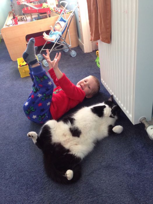 Мальчик копирует манеру кота лежать, задрав лапы кверху. 