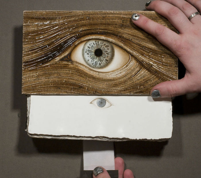 Используя акварель, акрил и сусальное золото, художник украшает книги витиеватыми изображениями человеческого глаза