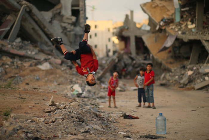 Мальчишки демонстрируют мастерство паркура в окружении разрушенных зданий Газа.