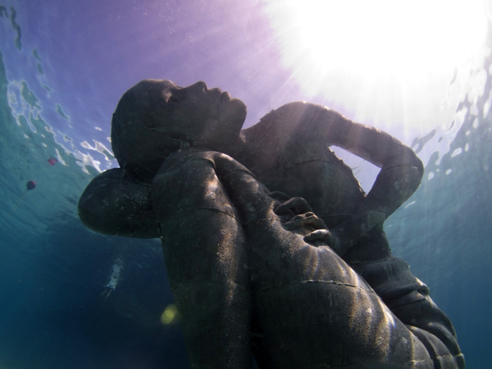 Гигантская подводная скульптура девушки на дней океана.