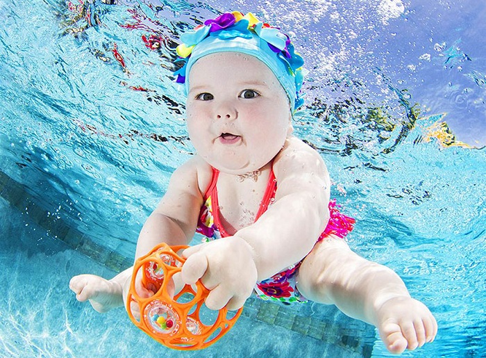 Малышка, которая учится плавать под водой.
