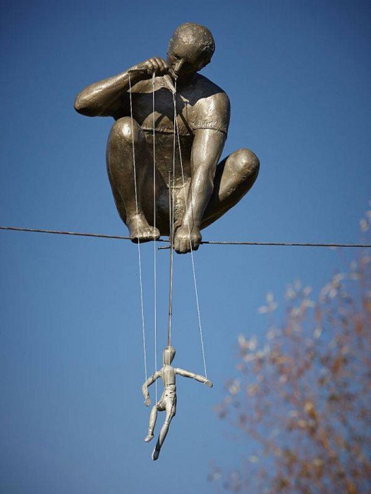 Кукольник с марионеткой, сидящий на канате. Сад скульптур Энн Нортон в Уэст-Палм-Бич штата Флорида.