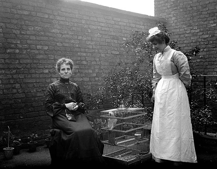 Миссис Диксон и Элис позируют рядом с клеткой с попугаем. Лондон.