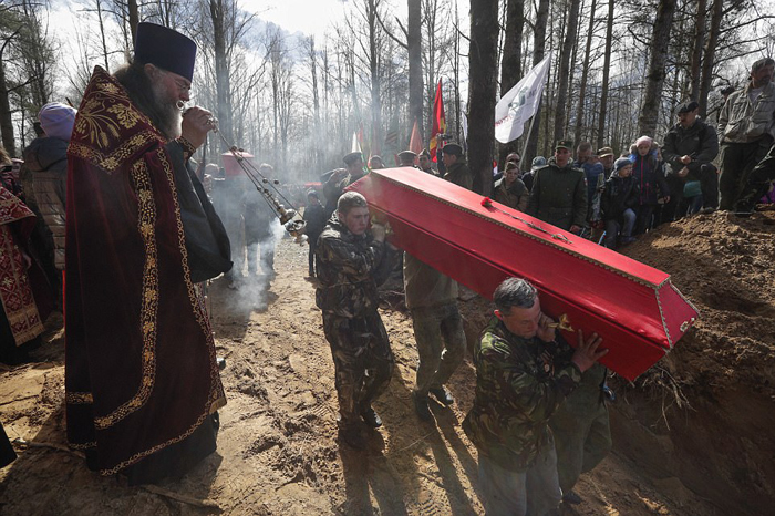 Люди наблюдают, как несут 41 гроб с останками погибших бойцов на место их нового захоронения. Останки 602 бойцов были захоронены в Синявино Ленинградской области.