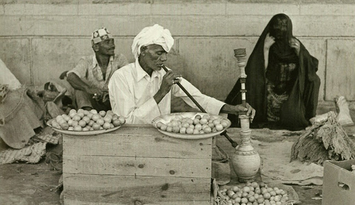 Мужчина, курящий кальян, продает лимоны и сушеные травы.