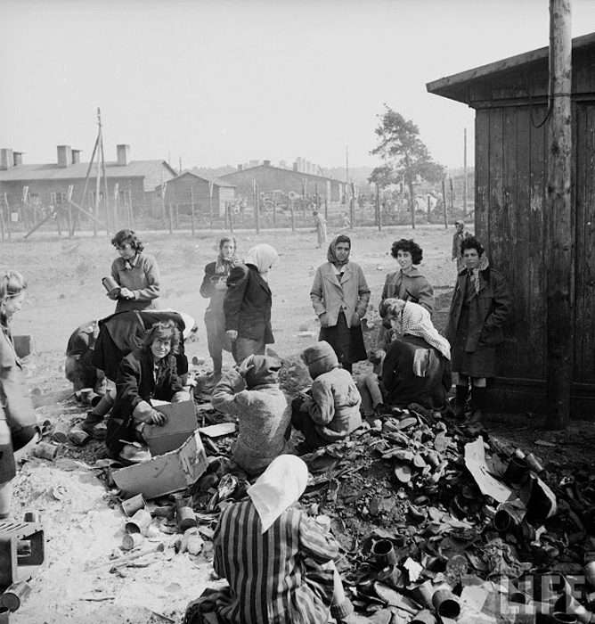 Женщины-заключенные сидят на груде мусора в ожидании еды.