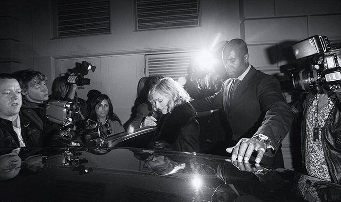Телохранитель помогает Мадонне пробраться к ожидающему ее автомобилю. Фото: Max Butterworth.