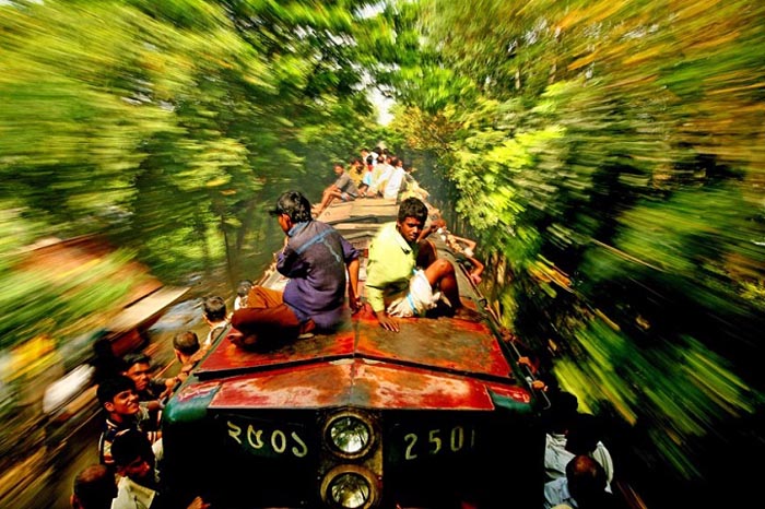 Некоторым пассажирам приходится ехать на подножке сбоку вагонов. Автор фото: GMB Akash.