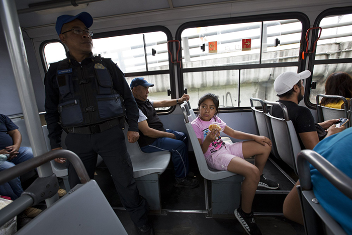 Полицейский офицер Хосе Осорио дель Анхель стоит дежурит в одном из автобусов, следующих из Истапалапа в центр Мехико.
