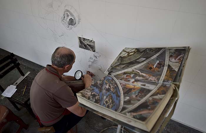 Волонтер Густаво Морено использует увеличительное стекло для воспроизведения деталей фрески.