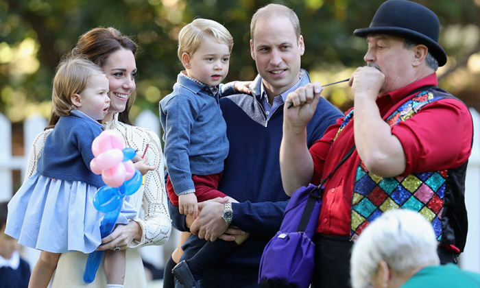 Кейт держит на руках Шарлотту в то время, как мужчина надувает шарик для принца Джорджа. Фото: Chris Jackson.