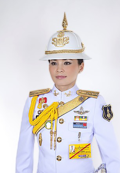 Королева позирует в белой военной форме, украшенной медалями.
