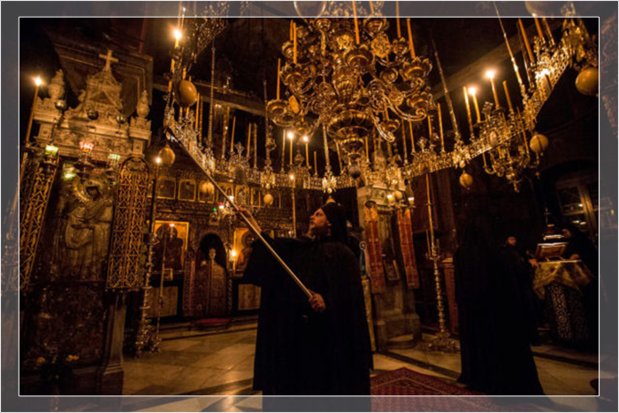 Монах зажигает свечи во время полуночного бдения в церкви монастыря Пантократор на Святой Горе Афон.