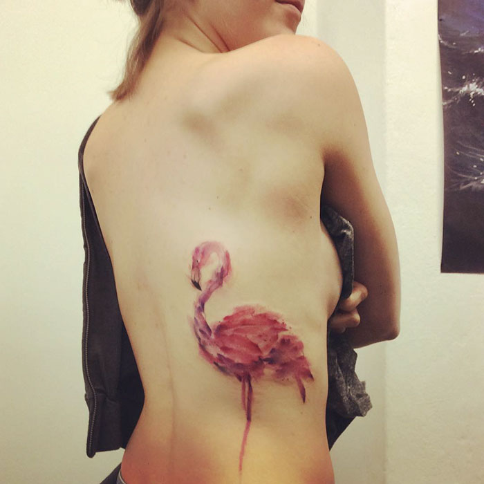 Изящное женское тело украшено изображением розового фламинго.