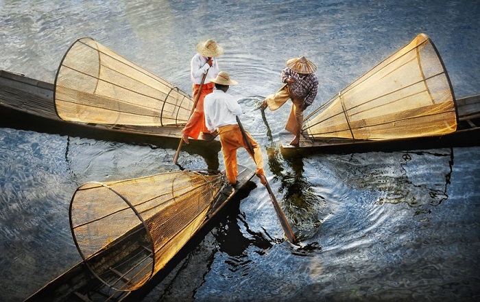 Рыбаки гребут веслом, зажатым в ноге, при этом у них свободны руки.