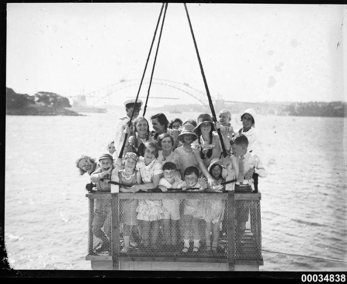  Группу детей поднимают в корзине на борт HMAS CANBERRA, 1931 год.