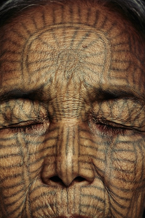Лицо пожилой женщины племени чин покрыто татуировками.
