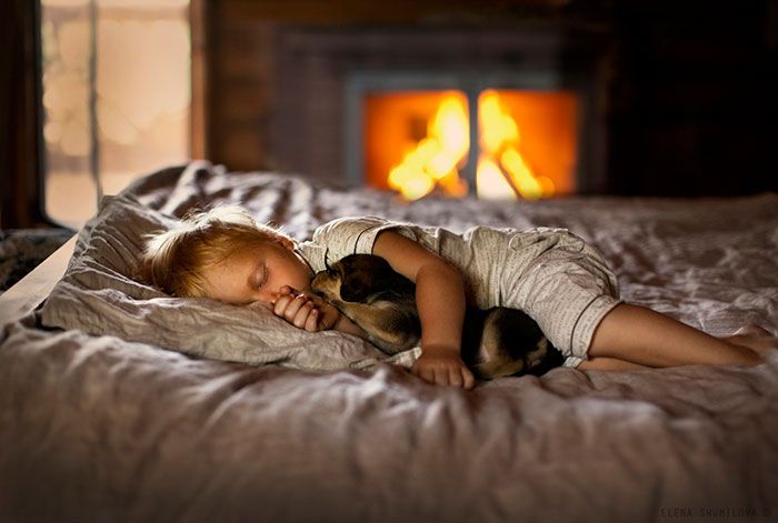 Ребенок спит в обнимку с щеночком.