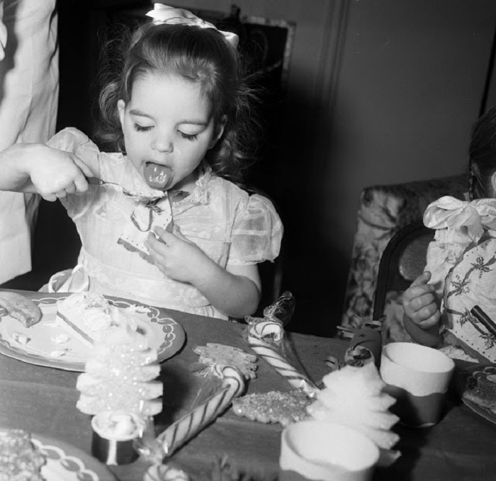 Лайза ест мороженое на рождественской вечеринке в доме Эдгара Бергена, куда она пошла с матерью Джуди Гарленд.