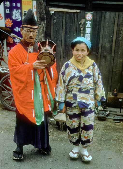 Мужчина и женщина, одеты в национальную одежду с ходят по улицам с музыкальным инструментом.
