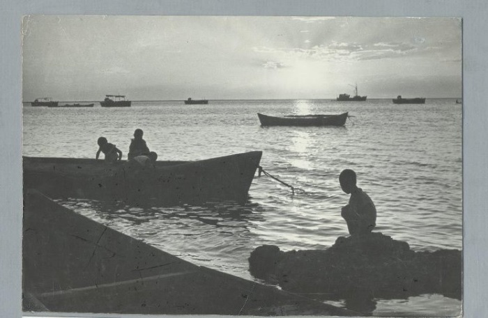 Ребятишки, играющие в лодке, которая пришвартована у каменистого берега Аральского моря.