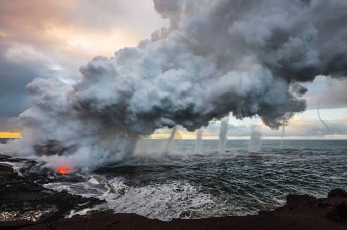 Выливающаяся в море огненная лава создает огромные шлейфы пара, порождая несколько вихрей.