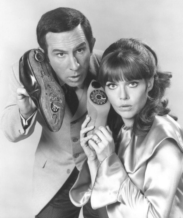 Молодая пара, изображающая шпионов с портативными телефонами того времени.