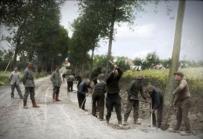 Немецкие солдаты надзирают за ходом выполнения ремонта дороги бельгийскими пленными.