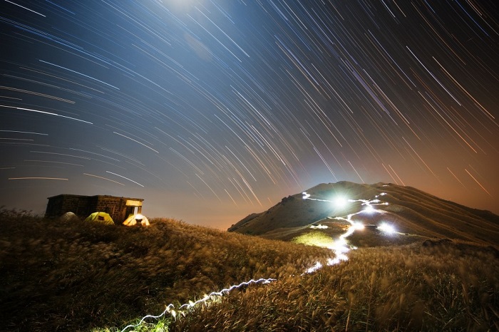 Над горой в Гонконге и на еще более дальнем расстоянии звезды как будто горят в ночном небе, оставляя за собой следы, но на самом деле они изображают движение Земли вокруг своей оси. Фотограф Chap Him Wong.