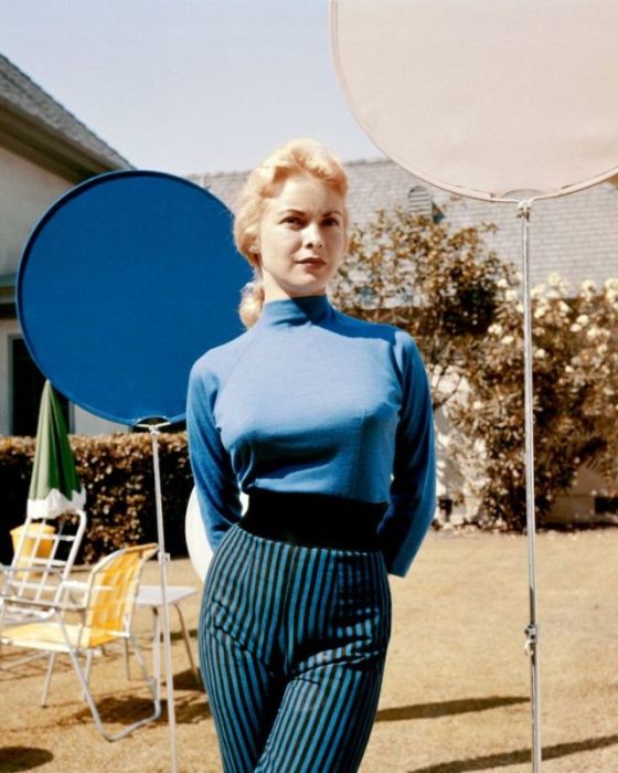 Женщина в брюках с завышенной талией в полоску и синей кофте.