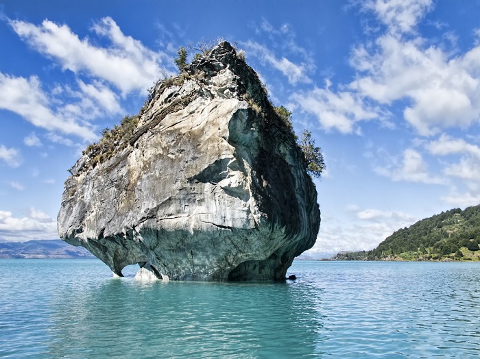 Яркие синие пещеры, частично погруженные в бирюзовые воды озера Каррера.