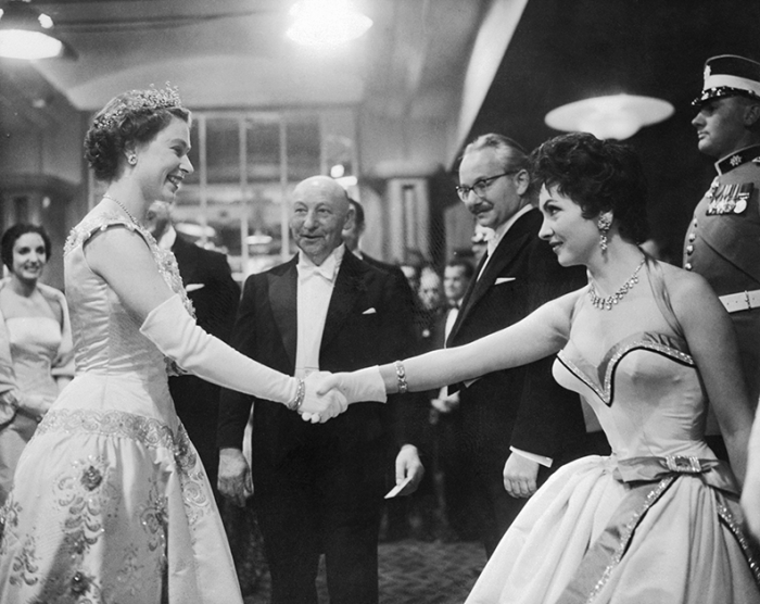 Джина Лоллобриджида пожимает руку королеве Елизавете II на премьере фильма «Поймать вора». Англия, Лондон, 1954 год.