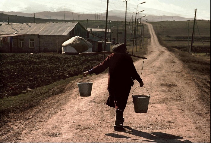 Женщина с ведрами, наполненными питьевой водой, на дороге одного из сел Армении.