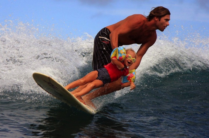 Папа обучает дочку сёрфингу.