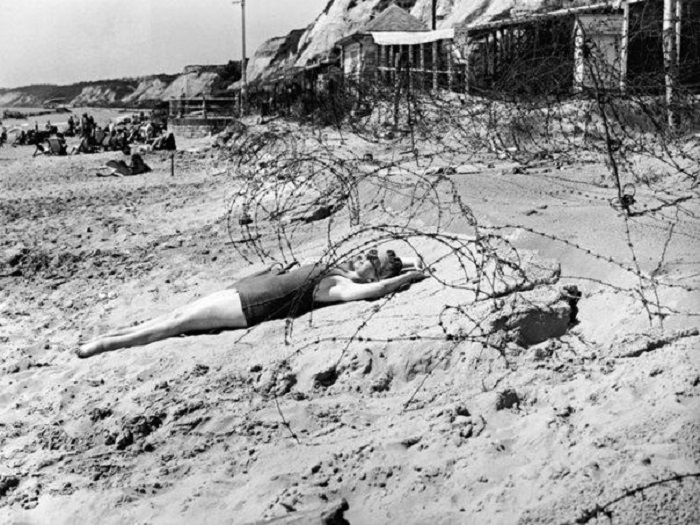 Женщина загорает в военное время в окружении колючей проволоки на пляже в Борнмуте, 1944 год.