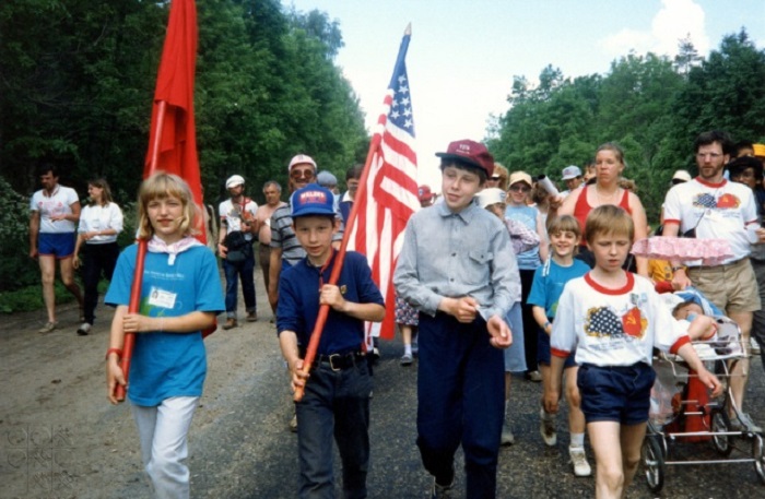Советский мальчик с звездно-полосатым флагом США и американская девочка с советским флагом во время шествия из Москвы в Ленинград в 1987 году.
