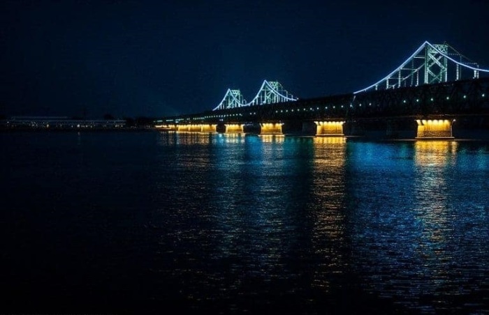 Освещенный мост с китайской стороны и погруженный во тьму на берегу Северной Кореи.