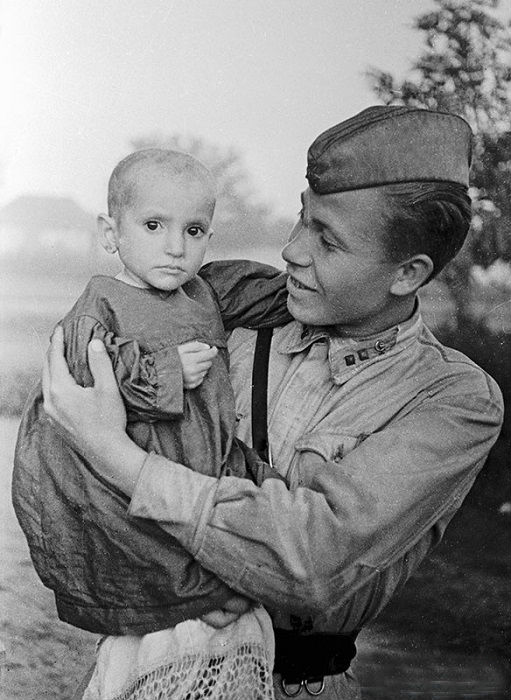 Советский офицер держит на руках спасенную им девочку из деревни Эльхотово, 1942 год. 