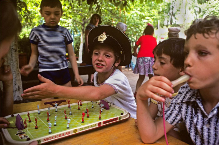 Группа детей играет в настольную игру на площадке.