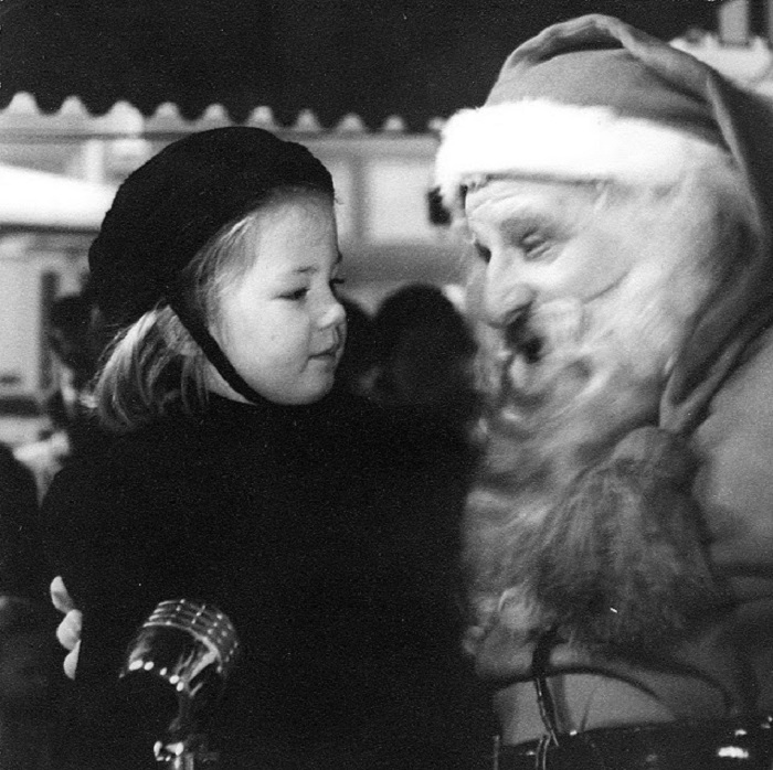 Девочка и Санта в канун Рождества поют рождественские песни.