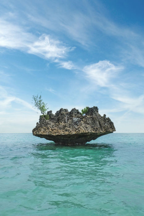 Небольшой одинокий остров с зелеными насаждениями в водах океана.