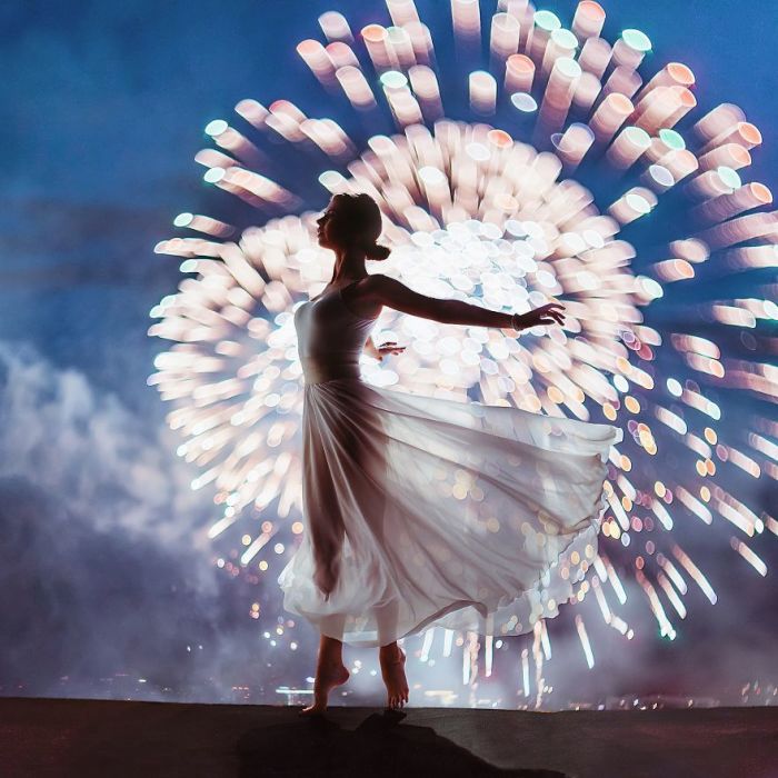 Изящная Нина в легком белом платье и ярких отблесках огней фестиваля фейерверков в Москве, Россия.
