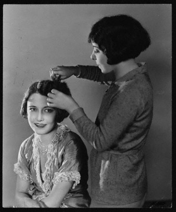Девушки делают укладку волос, отделяя прядь от пряди.