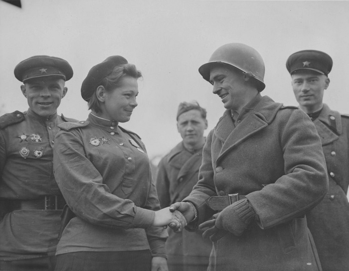 Советская военнослужащая пожимает руку американскому солдату.