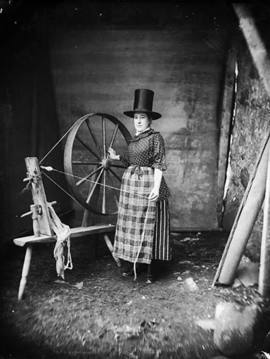 Женщина в национальном валлийском костюме и традиционной шляпе позирует у прялки фотографу Джону Томасу в 1885 году.