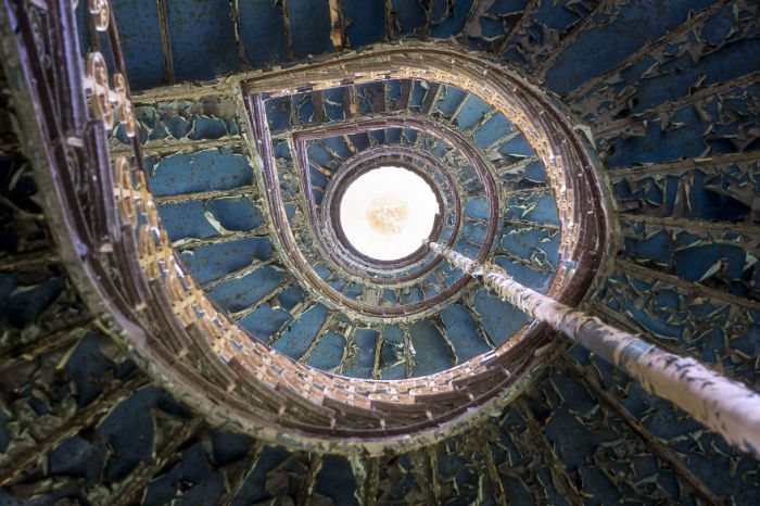 Спиральная лестница с голубой потрескавшейся краской в одном из опустевших польских дворцов.